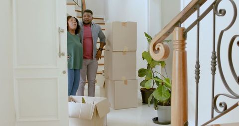 Happy Couple Unpacking Boxes in New Home and Celebrating Move