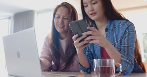 Asian mother and daughter sharing smartphone at home