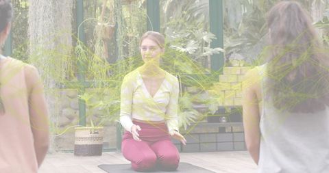 Kneeling Yoga Instructor Guiding Students in Conservatory Meditation with Tropical Plants