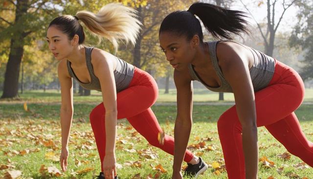 Female athletes starting sprint drill in autumn park wearing grey tanks red leggings