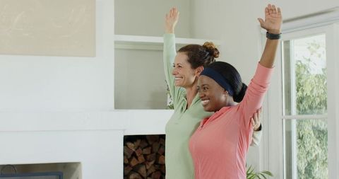 Diverse female friends stretching in home living room by fireplace