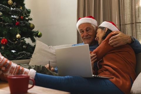 Senior Couple Embracing on Christmas With Laptop and Tree
