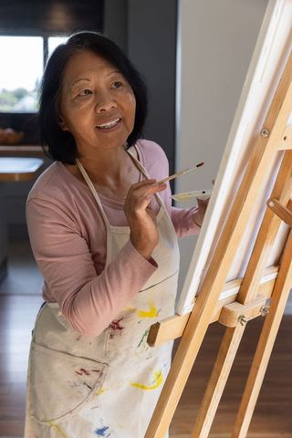 Senior Asian Woman Painting on Canvas in Kitchen