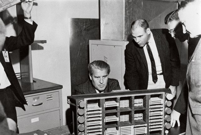 This photograph is dated March 10, 1966, and shows Dr. von Braun (seated) examining a Saturn computer in the Astrionics Laboratory at the Marshall Space Flight Center. Standing left to right are J.B. White, Brooks Moore, and Herman K. Weidner.
