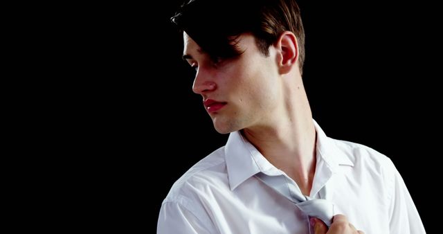 Young Man Adjusting Tie Against Black Background Close-Up - Download Free Stock Images Pikwizard.com