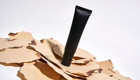 Minimalist matte black squeeze tube standing on torn kraft paper for skincare mockup label