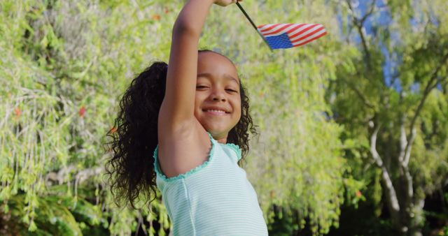 This vibrant image of a smiling girl joyfully waving an American flag is perfect for representing patriotism, USA celebrations, and positive summer vibes. It can be used for promoting national holidays such as Independence Day, Memorial Day, or other patriotic events. The cheerful expression and natural background can also be used to convey themes of happiness, childhood, and freedom.