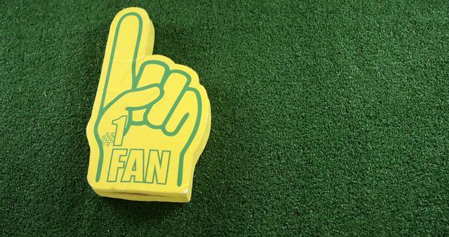 A #1 FAN yellow foam finger symbolizes team support on a green background. - Download Free Stock Photos Pikwizard.com