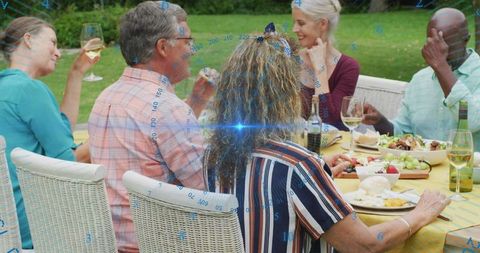 Friends enjoying outdoor dinner party sharing wine, cheese, fruit, lively conversation