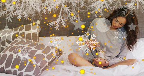 Woman relaxing with kitten on bed in winter-themed room