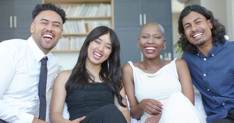 Laughing friends sharing joyful moment on couch in bright modern living room
