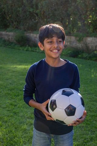 South Asian Boy Enjoying Soccer Outdoors on Sunny Day