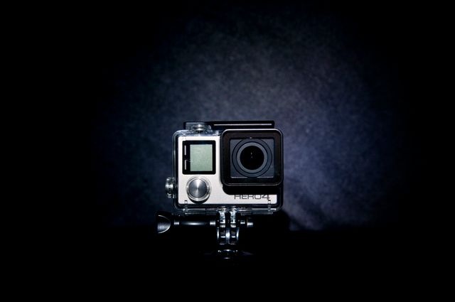 Front view of an action camera with a dark background. Ideal for articles or blogs about filming equipment, video recording, or action photography. Can be used in promotional materials for tech and gadget reviews or product features.