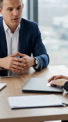 Vertical corporate meeting: Businessman explaining plan while colleague advancing slide on trackpad