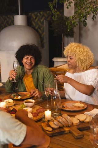 African american friends enjoying charcuterie and wine on cozy outdoor patio at dusk