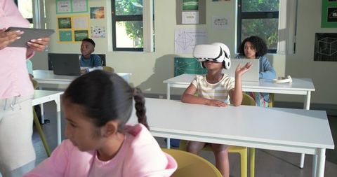 African American students using VR headset and laptops in modern classroom learning