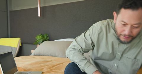 Mature adult using laptop in bedroom for productivity and relaxation