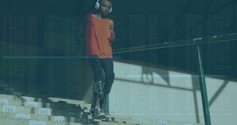 Teen Athlete with Prosthetic Blade Listening to Music on Bleachers