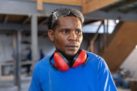 African american craftsman wearing safety goggles and ear protection standing in workshop