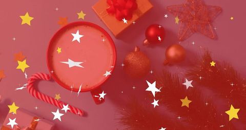 Festive red mug sitting on pink tabletop with star overlays, ornaments and candy cane
