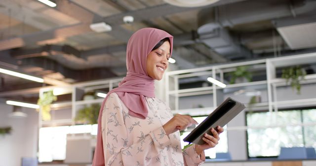 Smiling Businesswoman in Hijab Using Tablet in Modern Office - Download Free Stock Images Pikwizard.com