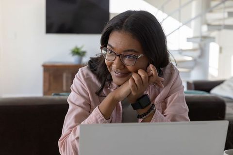 Smiling woman enjoying relaxing home environment with laptop