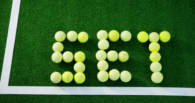 Bright tennis balls spelling out 'SET' on a lush grass court, symbolizing game and match dynamics. Ideal for sports, tennis-themed marketing, promotional materials, sporting events, and creative advertisements.