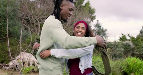 Interracial Couple Twirling and Embracing in Woodland Park, Playful Romantic Moment