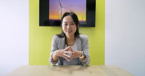 Asian businesswoman presenting sustainable energy pitch in modern minimalist office