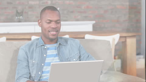 Man Smiling While Using Laptop at Comfortable Home Setting