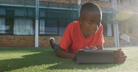 Young Boy Enjoying Tablet Outdoors on Grass