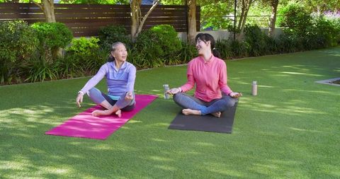 Mother and Daughter Practicing Yoga on Outdoor Mats in Garden