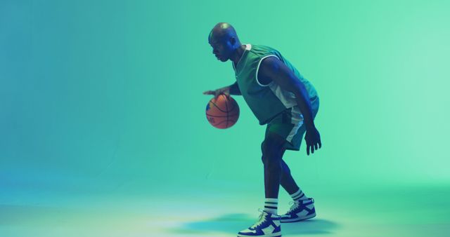 Image of african american male basketball player bouncing ball on blue background. Sports and competition concept.