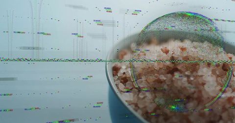 Digital glitch revealing magnified pink rock salt in white-rim bowl on blue surface