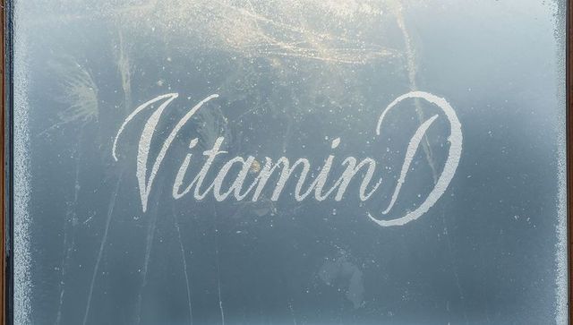 Cursive vitamin d script etching on frosted glass door backlit by morning sunlight