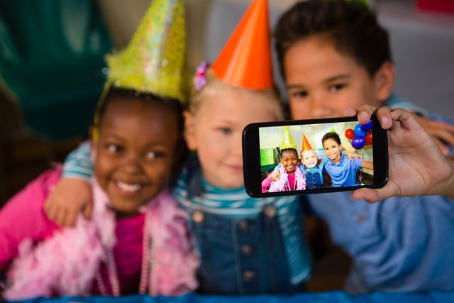 Children talking selfie through smartphone during birthday party