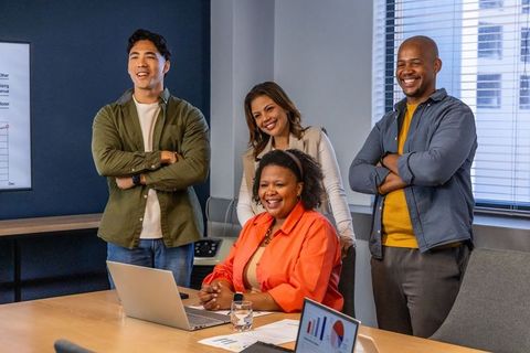 Multicultural team collaborating during casual office presentation with laptops and charts