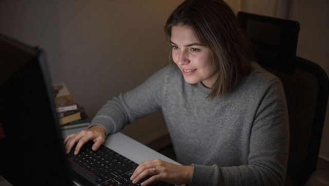Focused Woman Using Computer in Cozy Evening Home Office
