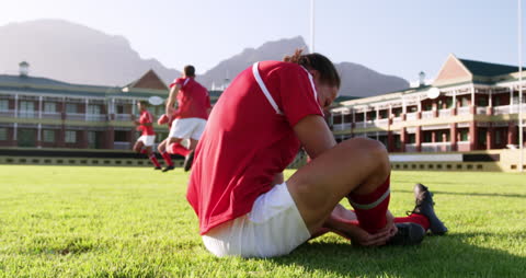 Injured Rugby Player Holding Ankle on Field