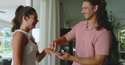 Man gifting a romantic surprise to smiling woman at home