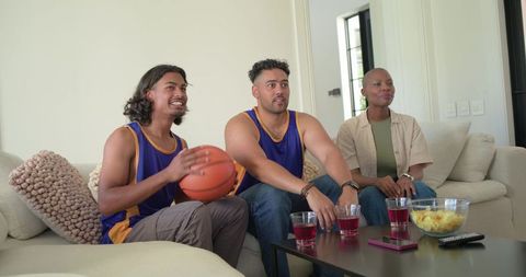 African american friends watching and cheering during basketball game in living room