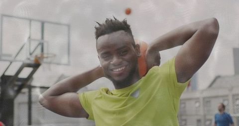 Smiling young athlete holding orange basketball at urban outdoor court in neon green tee