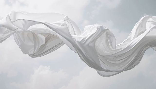 White fabric gracefully flowing against cloudy sky