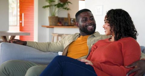 Smiling couple relaxing on sofa in modern open-plan living room