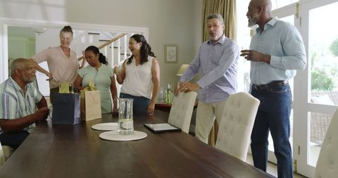 Diverse Senior Friends Celebrating with Drinks and Gifts at Home Gathering