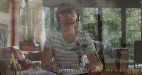 Girl studying wearing headset and glasses writing at desk with three crosses overlay