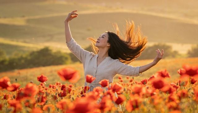 Dancing woman in poppy field at golden hour flowing hair linen dress sunlit countryside