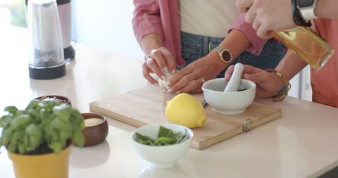 Couple preparing fresh basil garlic lemon vinaigrette on kitchen countertop