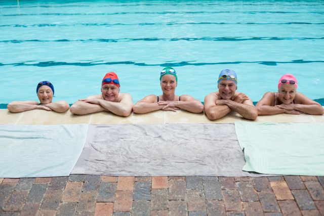 Portrait of senior swimmers leaning on poolside