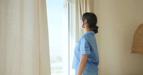 Nurse admiring urban view through window in daylight setting